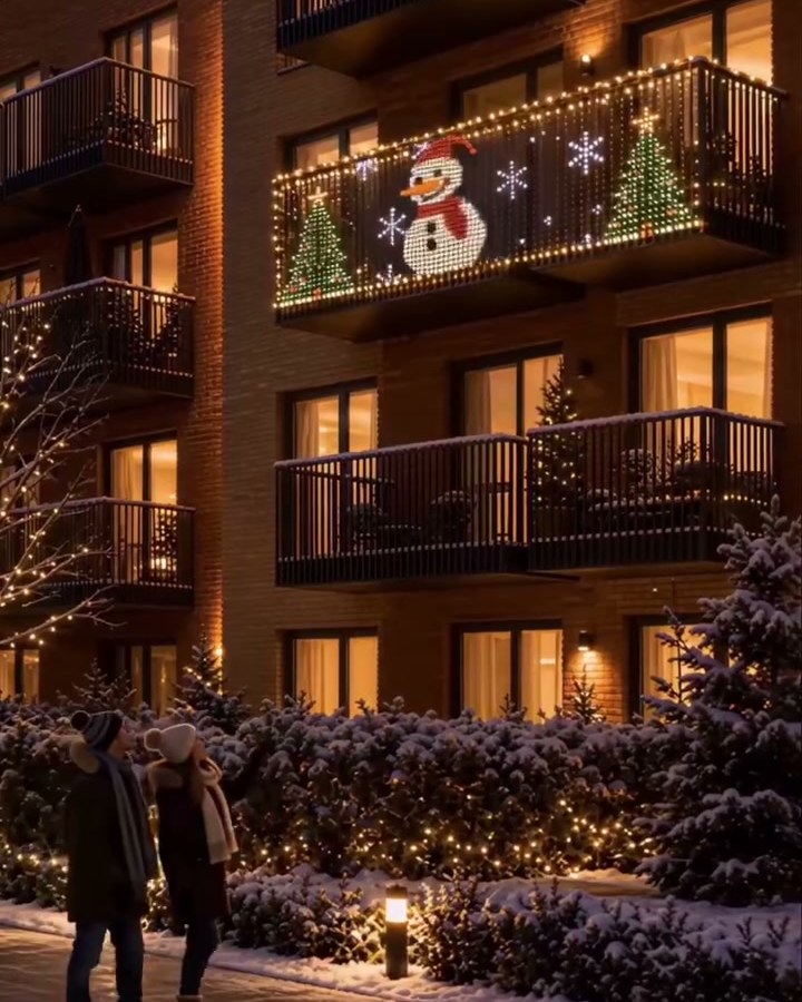Fachada de prédio à noite com o painel de LED de boneco de neve na sacada